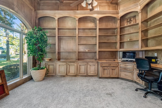 carpeted office featuring a healthy amount of sunlight, built in features, ceiling fan, and wooden walls