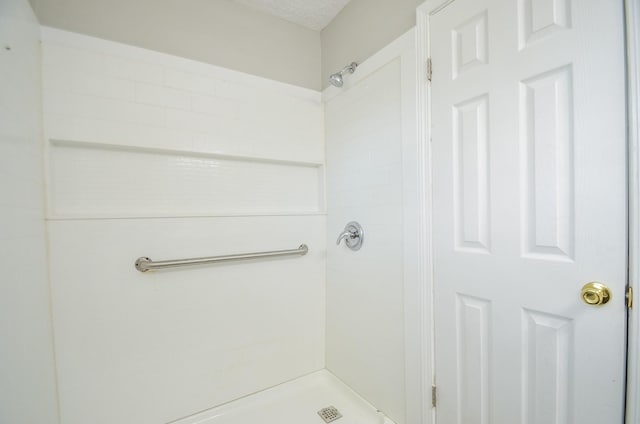 bathroom featuring a textured ceiling and tiled shower