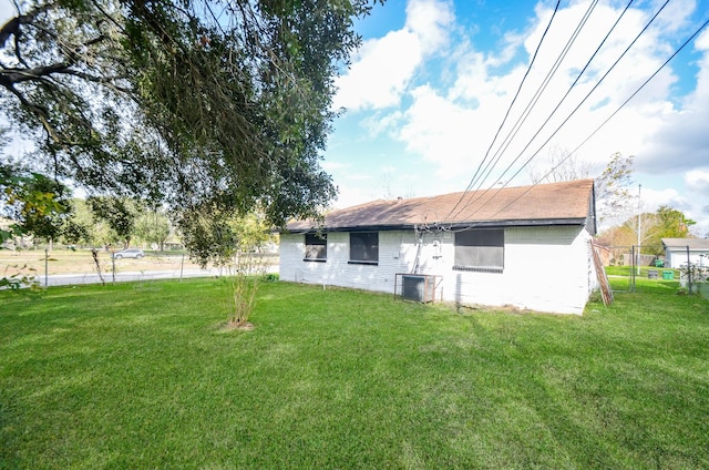 rear view of property featuring a lawn and central air condition unit