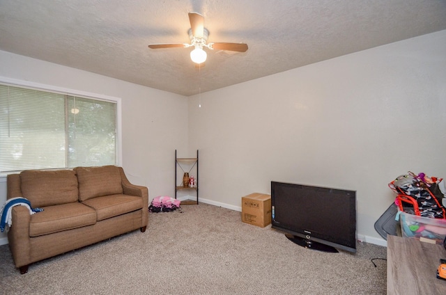 carpeted living room featuring ceiling fan and a textured ceiling