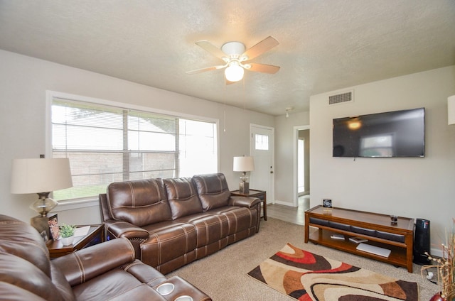 carpeted living room featuring a textured ceiling and ceiling fan