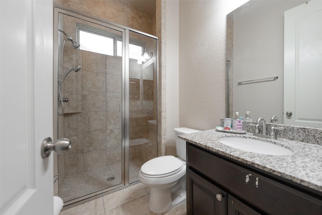 bathroom featuring tile patterned floors, vanity, a shower with shower door, and toilet