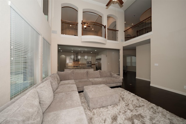 living room featuring a towering ceiling, hardwood / wood-style flooring, and ceiling fan