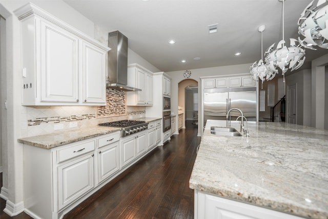 kitchen with sink, wall chimney exhaust hood, dark hardwood / wood-style flooring, pendant lighting, and white cabinets