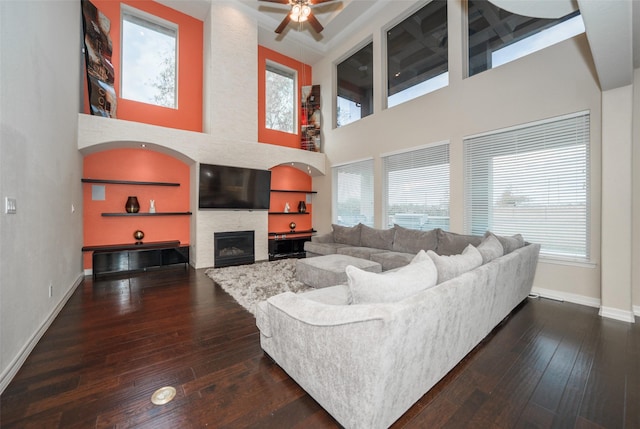 living room with ceiling fan, dark hardwood / wood-style floors, and a high ceiling