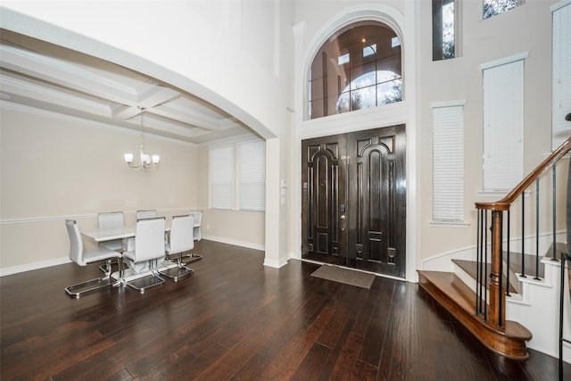 entrance foyer featuring coffered ceiling, dark wood-type flooring, an inviting chandelier, beamed ceiling, and a high ceiling