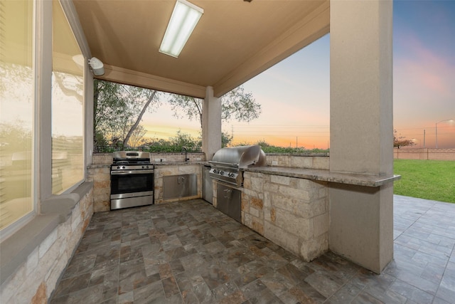 patio terrace at dusk with a grill, sink, and an outdoor kitchen