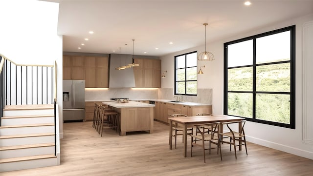 kitchen featuring stainless steel fridge, sink, pendant lighting, light hardwood / wood-style flooring, and a kitchen island