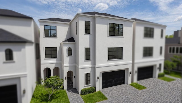 view of front of property featuring an attached garage, decorative driveway, and stucco siding