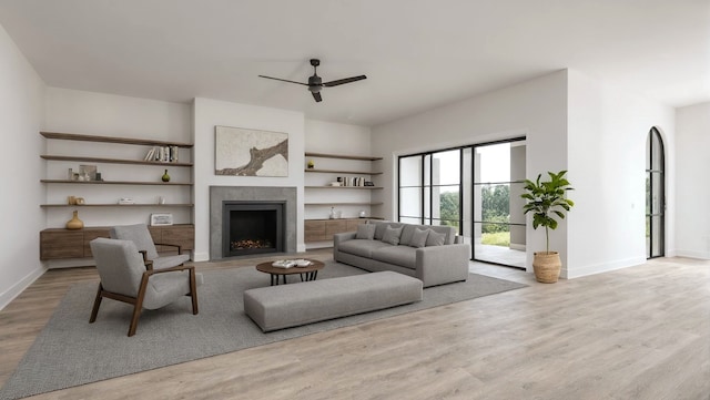 living area featuring light wood-style floors, a fireplace, baseboards, and a ceiling fan