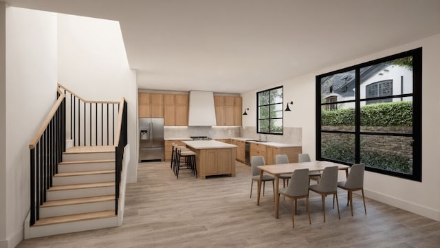 dining area featuring light wood-type flooring, baseboards, and stairs