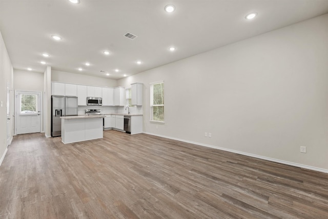 kitchen featuring white cabinets, a kitchen island, light hardwood / wood-style floors, and stainless steel appliances