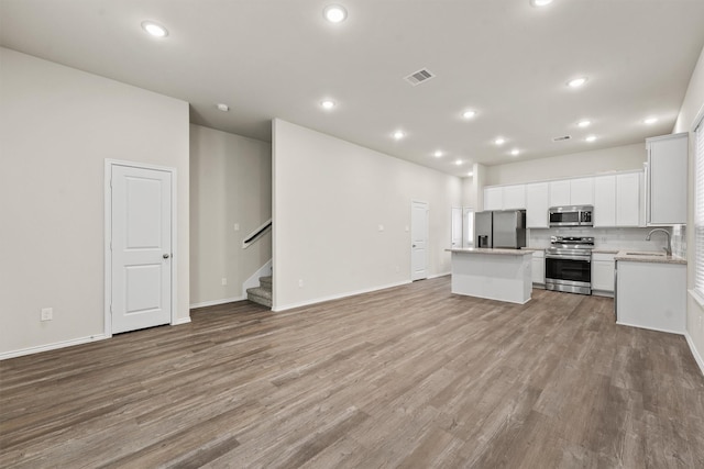 kitchen with sink, light wood-type flooring, a kitchen island, white cabinetry, and stainless steel appliances