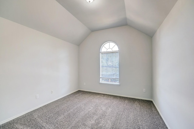 carpeted empty room featuring vaulted ceiling