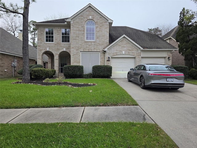 traditional-style home featuring a shingled roof, concrete driveway, a front lawn, a garage, and brick siding