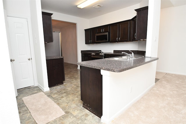 kitchen featuring sink, appliances with stainless steel finishes, dark brown cabinets, light colored carpet, and kitchen peninsula