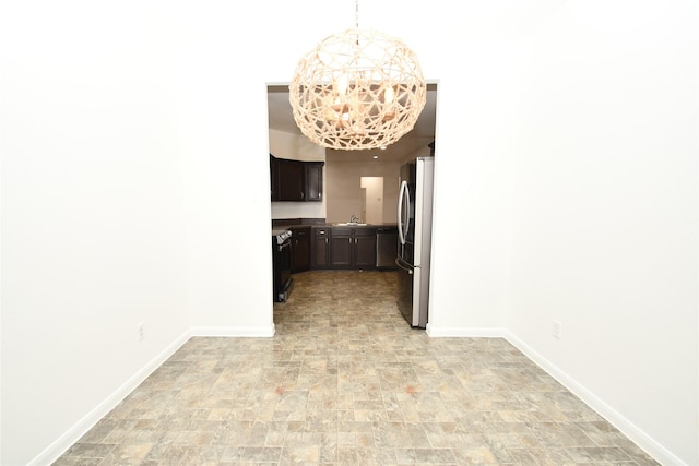 kitchen with a chandelier, dark brown cabinetry, and stainless steel refrigerator