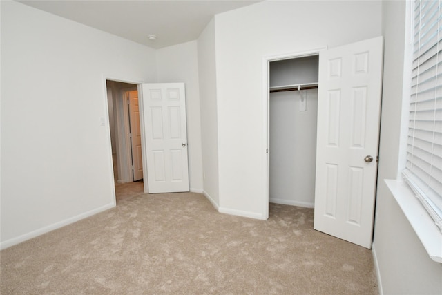 unfurnished bedroom with light colored carpet and a closet