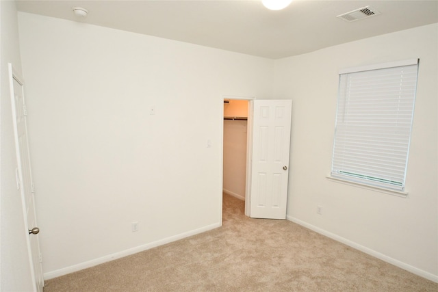 interior space featuring a walk in closet, light carpet, and a closet