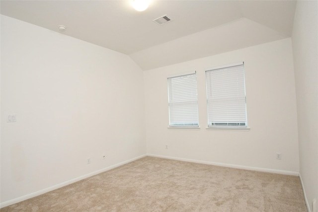 carpeted empty room with vaulted ceiling