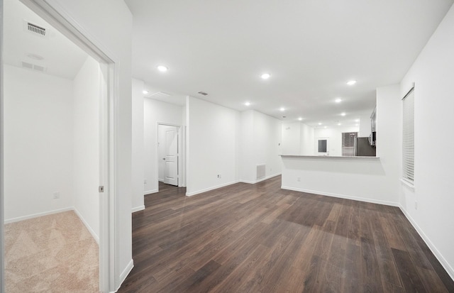 unfurnished living room with recessed lighting, visible vents, baseboards, and dark wood-style flooring