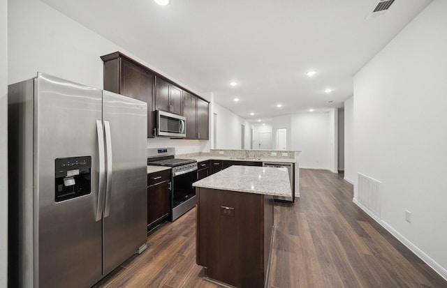 kitchen featuring visible vents, a sink, appliances with stainless steel finishes, a peninsula, and dark brown cabinets