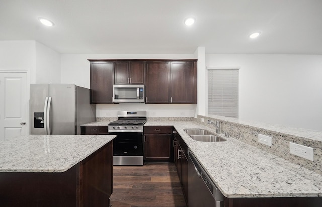 kitchen featuring a sink, light stone counters, dark wood finished floors, stainless steel appliances, and dark brown cabinets