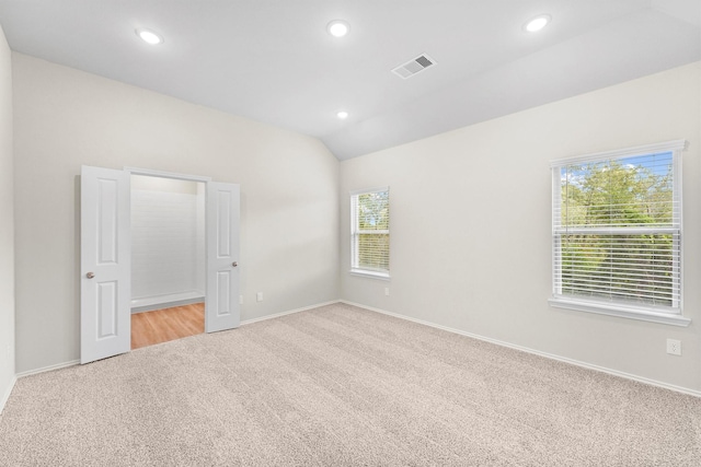 spare room featuring lofted ceiling and light carpet