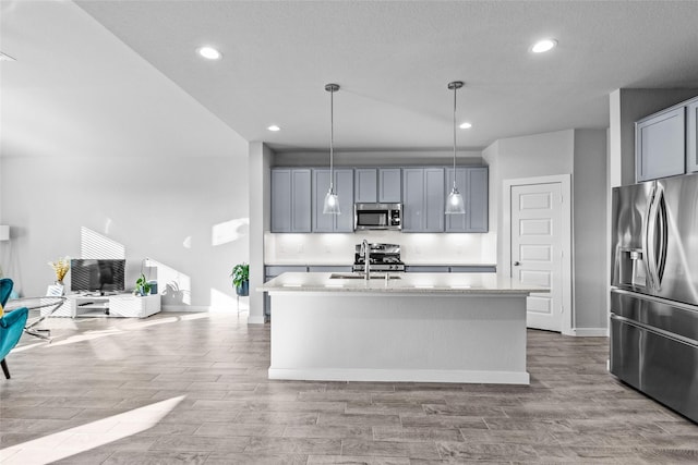 kitchen with gray cabinetry, an island with sink, and appliances with stainless steel finishes