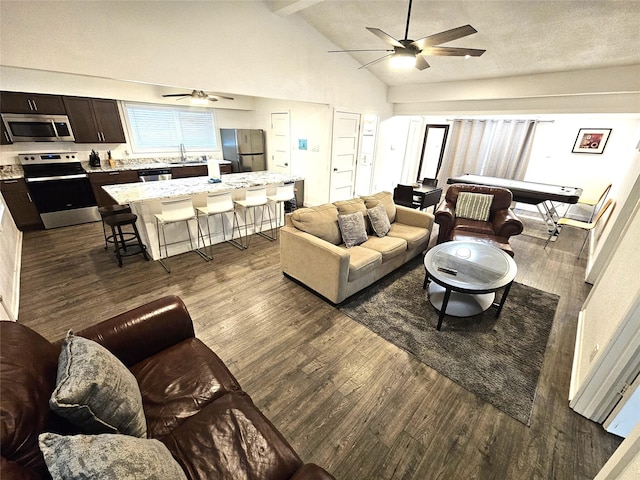 living room featuring dark hardwood / wood-style floors, high vaulted ceiling, beamed ceiling, ceiling fan, and a textured ceiling