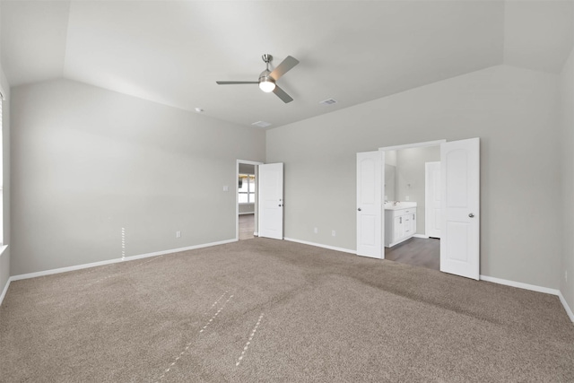 empty room with ceiling fan, lofted ceiling, and dark colored carpet