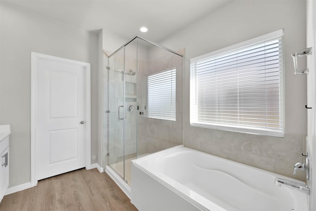 bathroom featuring plus walk in shower, wood-type flooring, and vanity