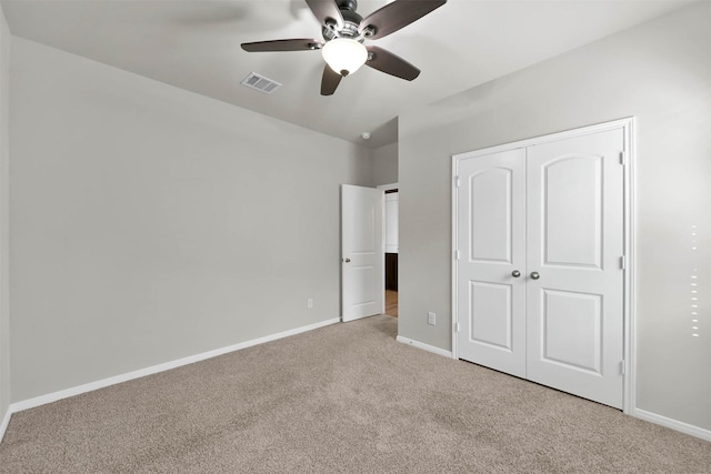 unfurnished bedroom featuring a closet, light colored carpet, and ceiling fan