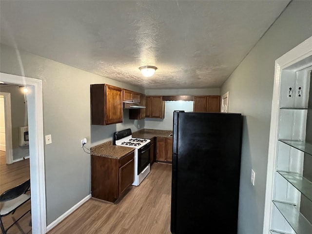 kitchen featuring black fridge, dark stone counters, a textured ceiling, white range oven, and light hardwood / wood-style flooring