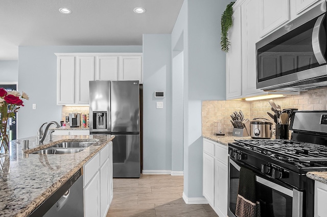 kitchen featuring light stone countertops, stainless steel appliances, and white cabinetry