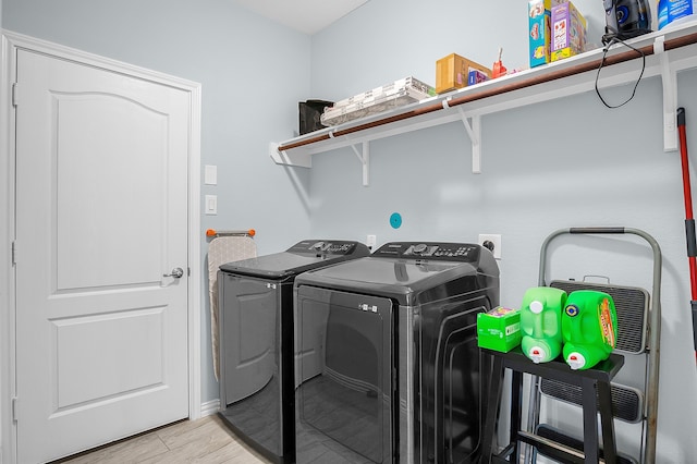 laundry area with light hardwood / wood-style flooring and washer and dryer