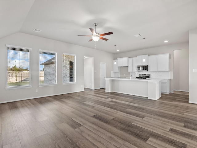 unfurnished living room featuring ceiling fan, sink, dark wood-type flooring, and vaulted ceiling