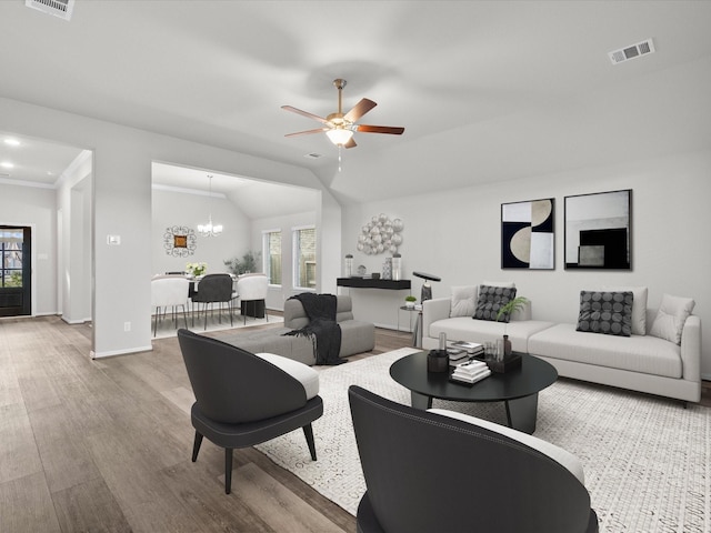 living room with hardwood / wood-style floors, ceiling fan with notable chandelier, and vaulted ceiling