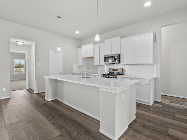 kitchen featuring appliances with stainless steel finishes, a kitchen island with sink, dark wood-type flooring, sink, and white cabinetry