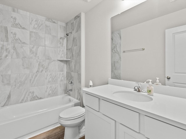 full bathroom featuring vanity, wood-type flooring, tiled shower / bath combo, and toilet