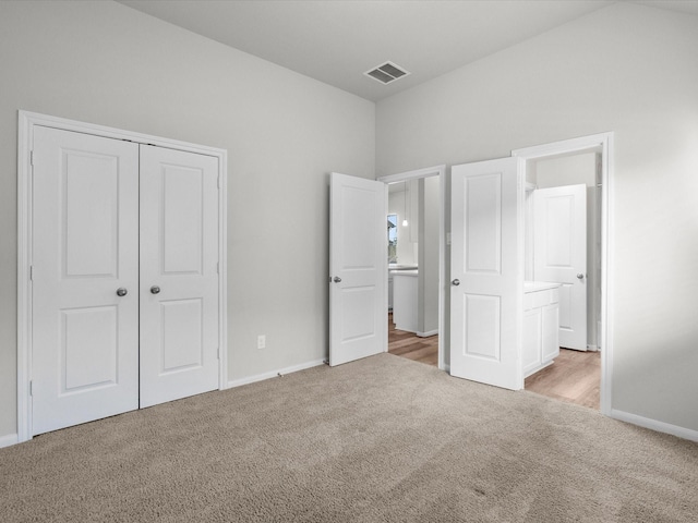 unfurnished bedroom with light carpet, connected bathroom, and a closet