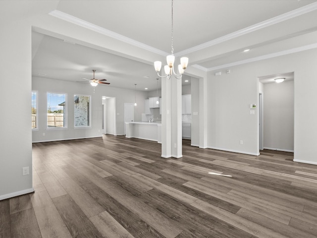 unfurnished living room with ceiling fan with notable chandelier, crown molding, and dark wood-type flooring