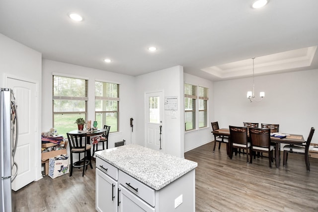 kitchen with white cabinets, hanging light fixtures, dark hardwood / wood-style floors, stainless steel fridge, and a chandelier