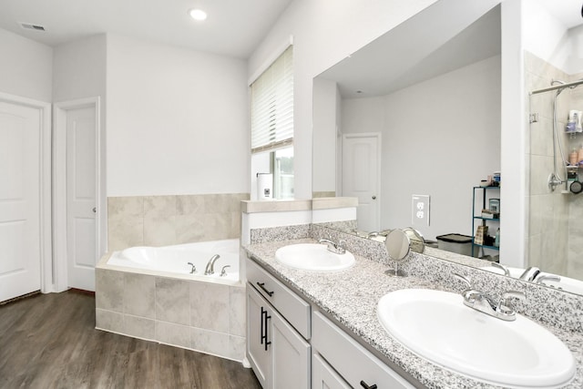 bathroom with hardwood / wood-style floors, vanity, and plus walk in shower