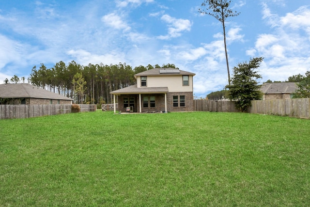 back of house featuring solar panels and a yard