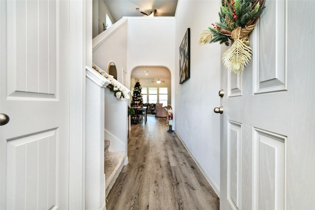 entryway with light wood-style floors, baseboards, stairway, and arched walkways