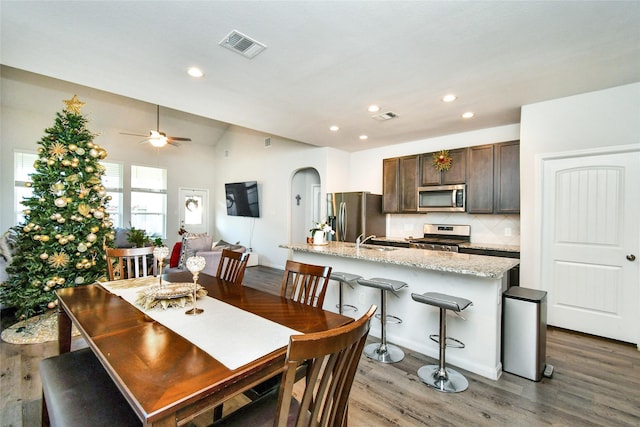 dining area featuring arched walkways, visible vents, recessed lighting, and wood finished floors