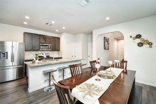 dining space featuring arched walkways, dark wood-type flooring, and visible vents