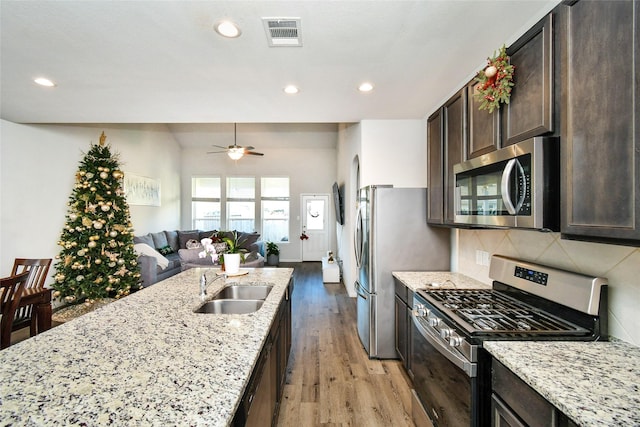 kitchen featuring stainless steel appliances, visible vents, a sink, and light stone counters