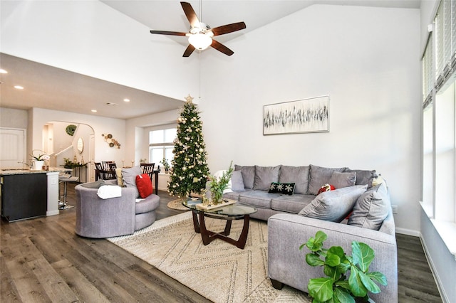 living area with arched walkways, dark wood finished floors, recessed lighting, ceiling fan, and high vaulted ceiling